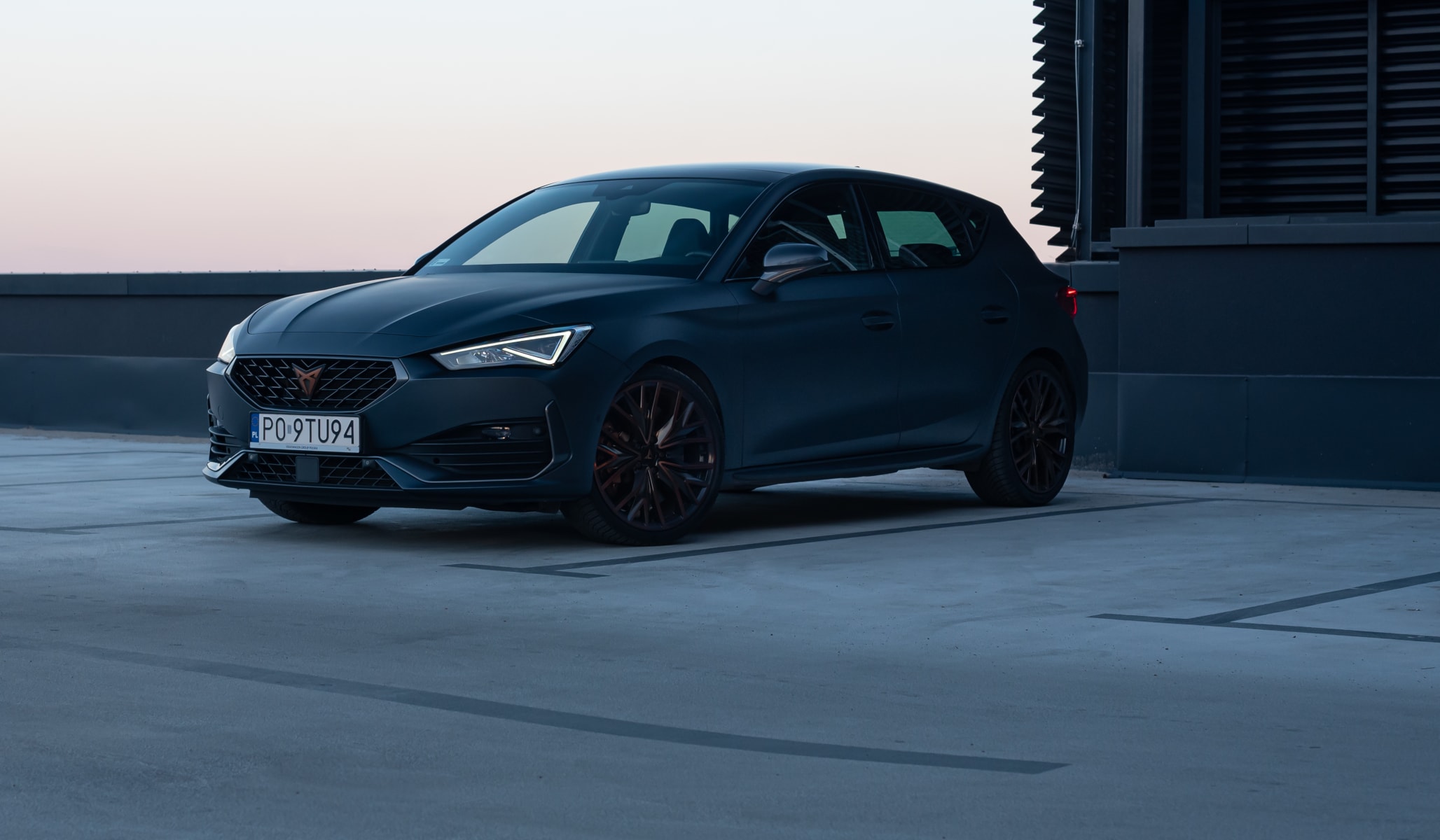  CUPRA Leon na parkingu dachowym. Zbliżenie na przednią część nadwozia