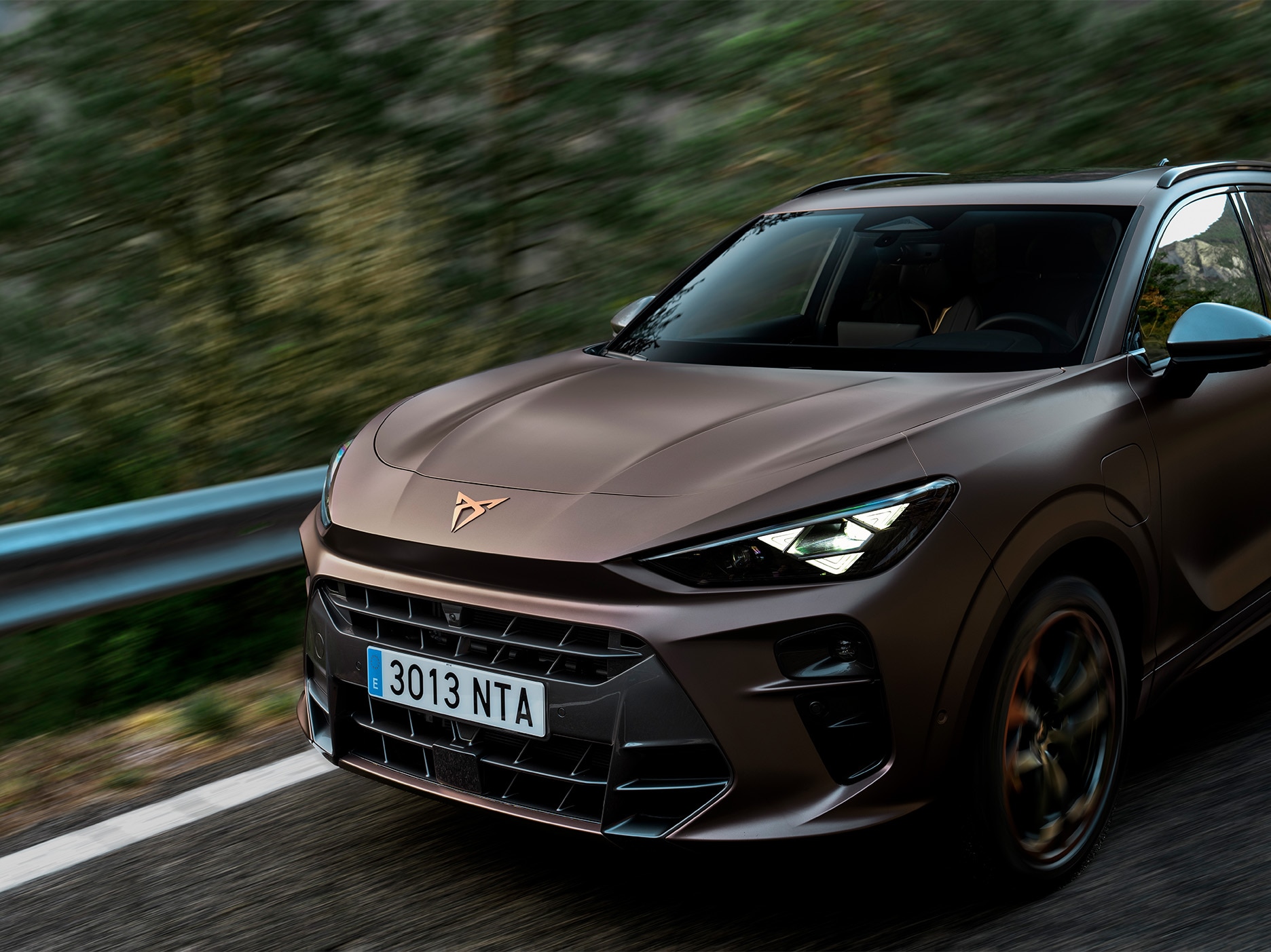 Ujęcie boczne modelu CUPRA Terramar w ruchu na drodze. Ujęcie podkreśla przednią część inspirowaną sylwetką nosa rekina, nadającą samochodowi wyjątkowy charakter.