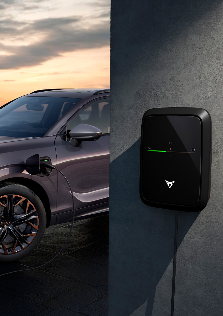 Widok z boku modelu CUPRA Terramar 2025 w kolorze Dark Void, zaparkowanego na zewnątrz, z widocznym punktem ładowania samochodu. 