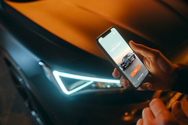 kobieta przeglądająca aplikację Cupra Connect obok samochodu