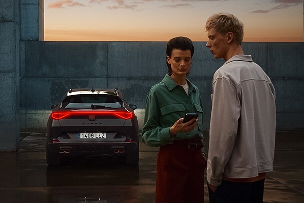dwie osoby korzystające z aplikacji cupra connect z samochodem cupra w garażu