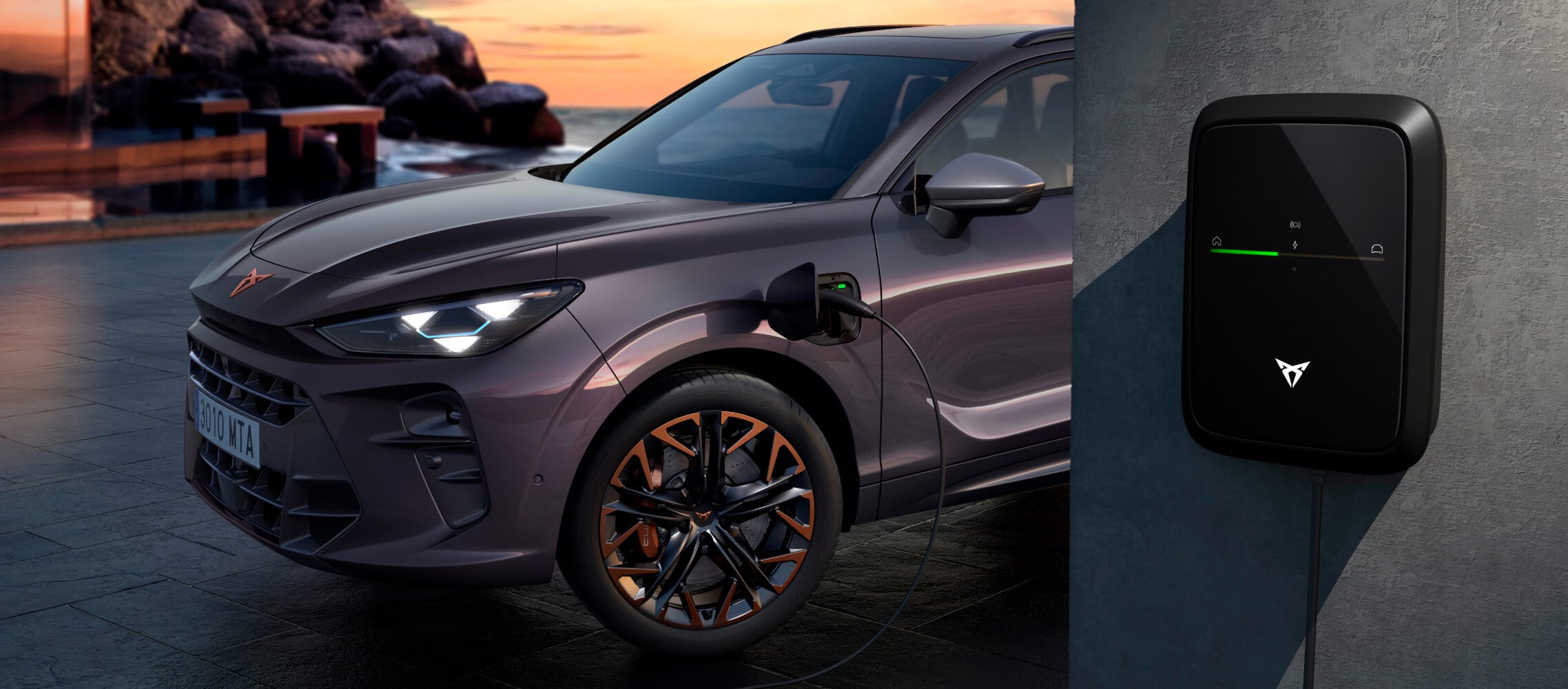 Samochód służbowy CUPRA Terramar VZ PHEV, przeznaczony dla flot, w kolorze Dark Void, zaparkowany podczas ładowania za pomocą ładowarki CUPRA, na tle malowniczej scenerii o zachodzie słońca.