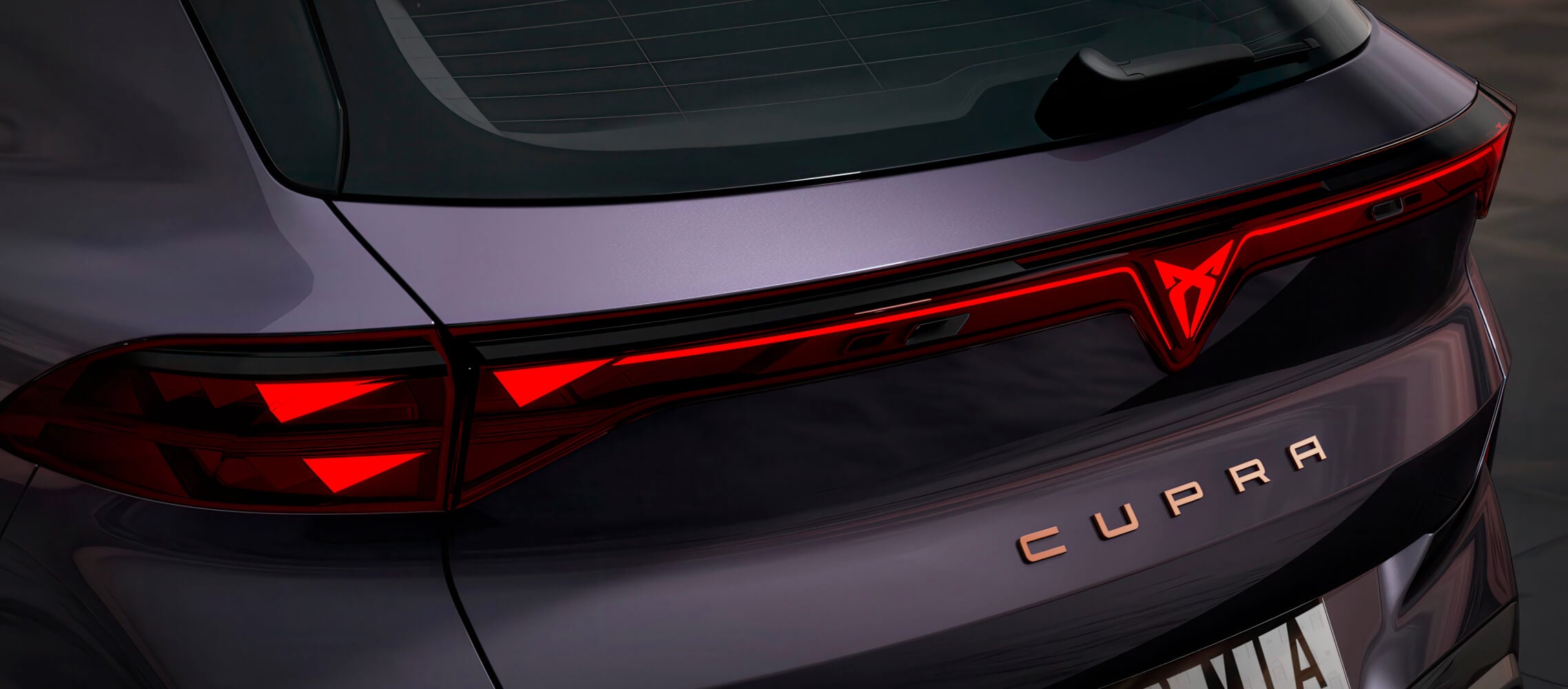 Zbliżenie tylnej części modelu CUPRA Terramar VZ w kolorze Dark Void, tylne światła z podświetlanym logo i miedzianymi akcentami.