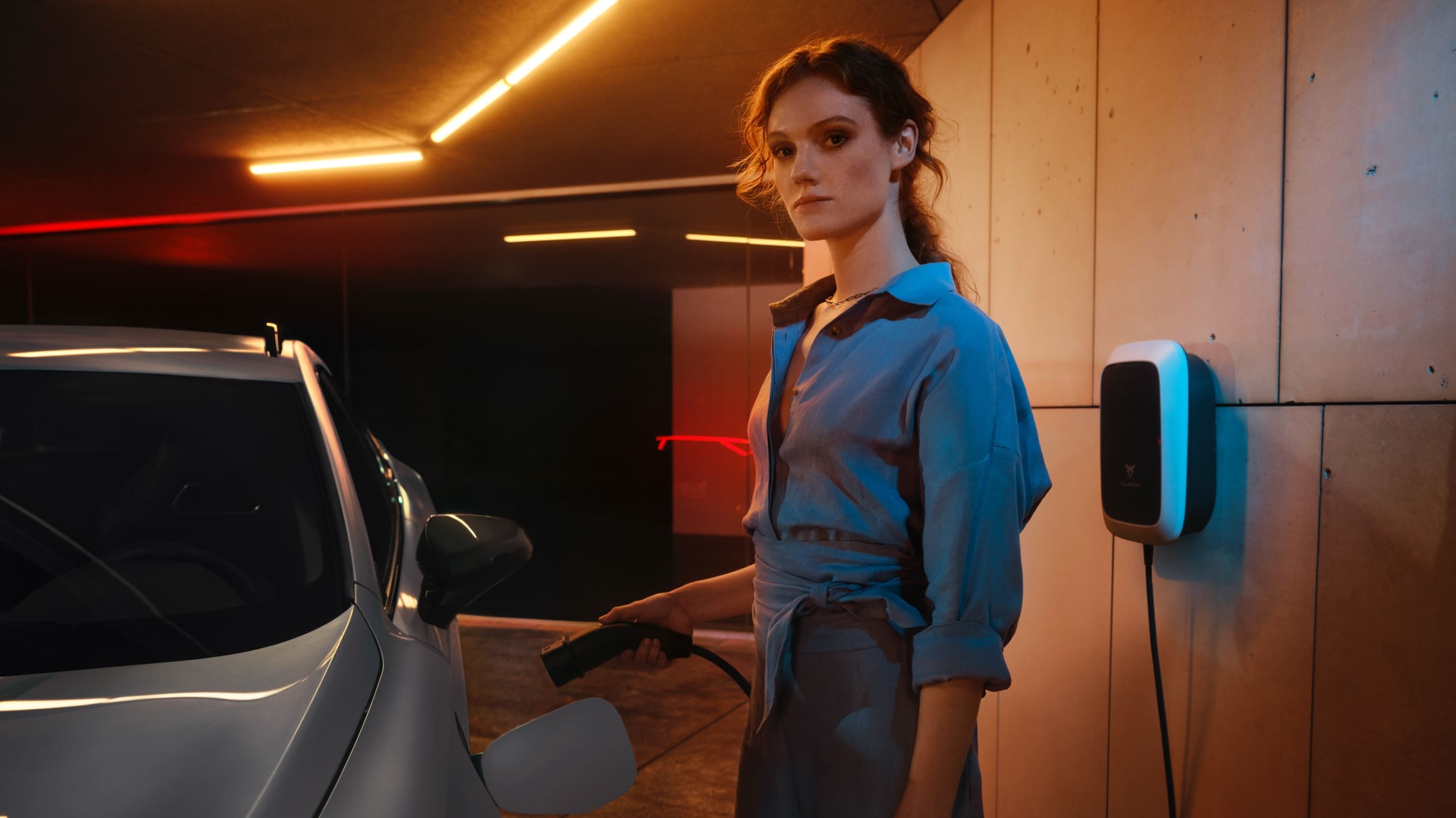 Kobieta ładująca samochód cupra formentor e-hybrid za pomocą ładowarki ściennej cupra charger
