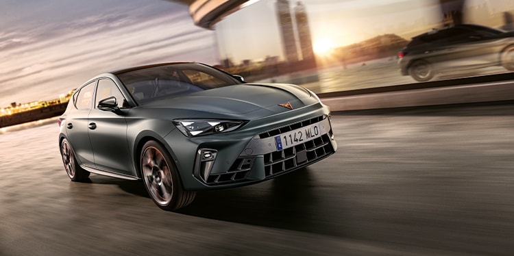 phev CUPRA Leon Sportstourer w ruchu, miejska sceneria o zachodzie słońca